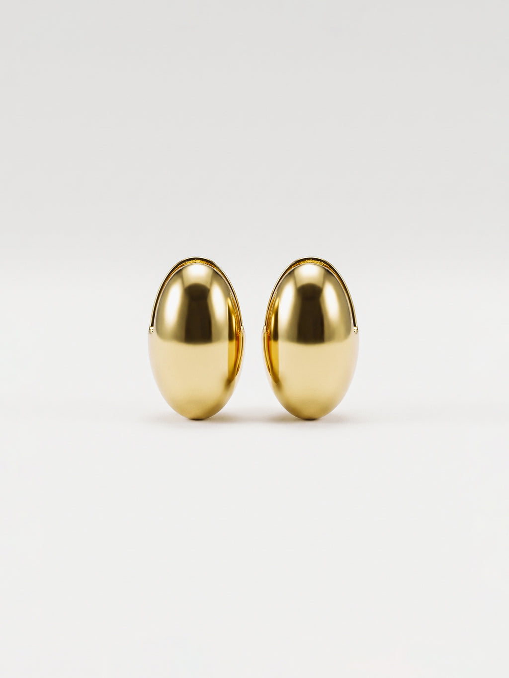 A pair of gold egg shaped earrings with a polished, metallic finish, displayed against a clean white background.