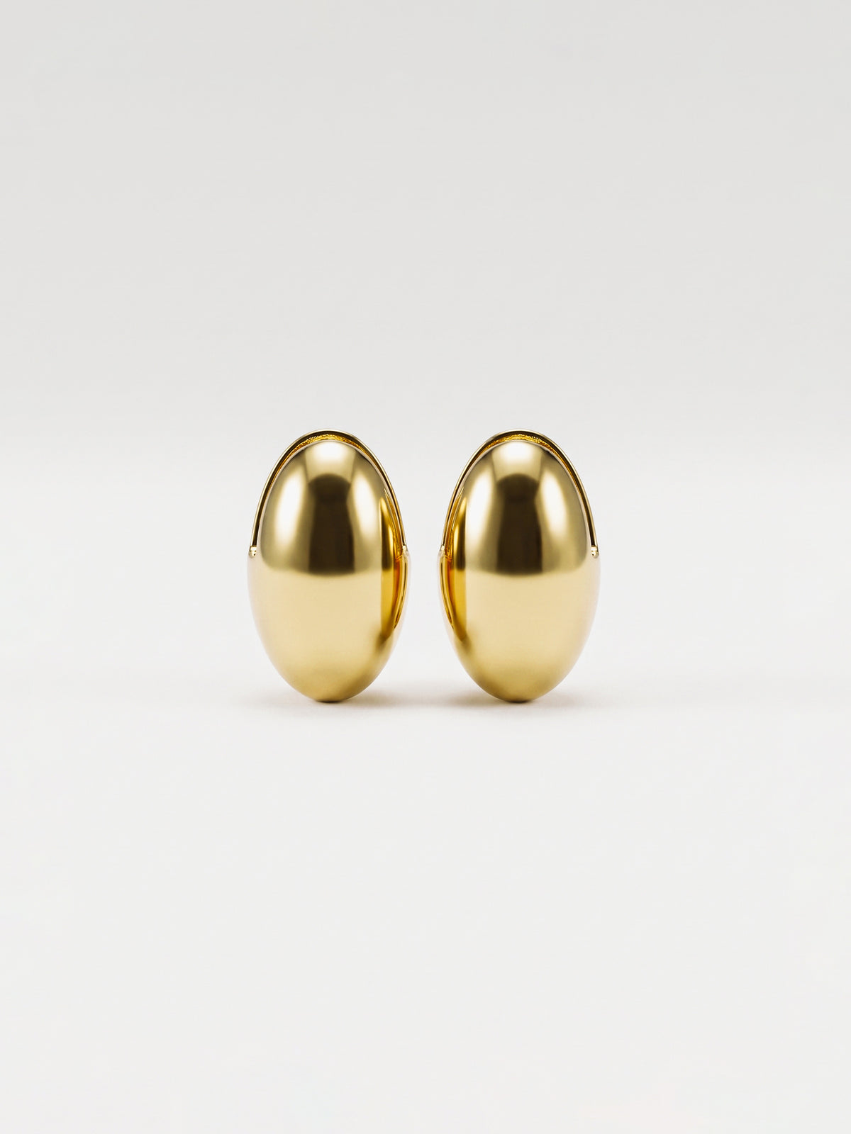 A pair of gold egg shaped earrings with a polished, metallic finish, displayed against a clean white background.