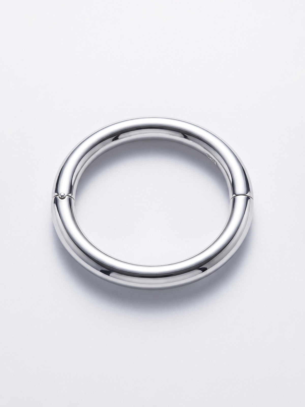 A polished silver ellipse bangle with a small hinge on one side, shown on a clean white background.