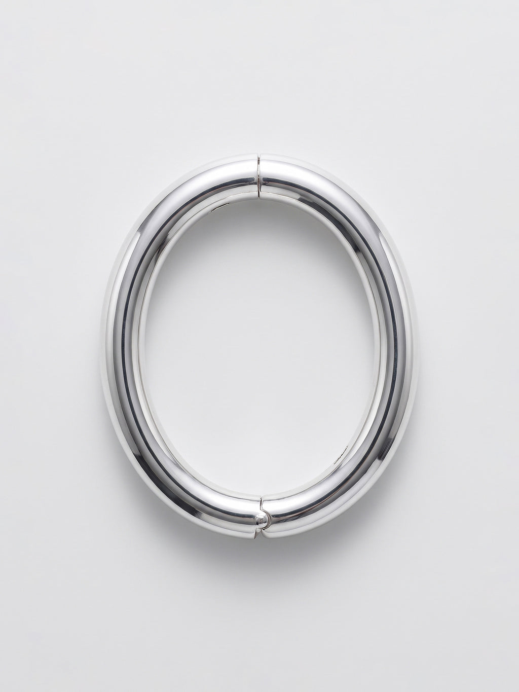A polished silver ellipse bangle shown from the front on a light gray background.