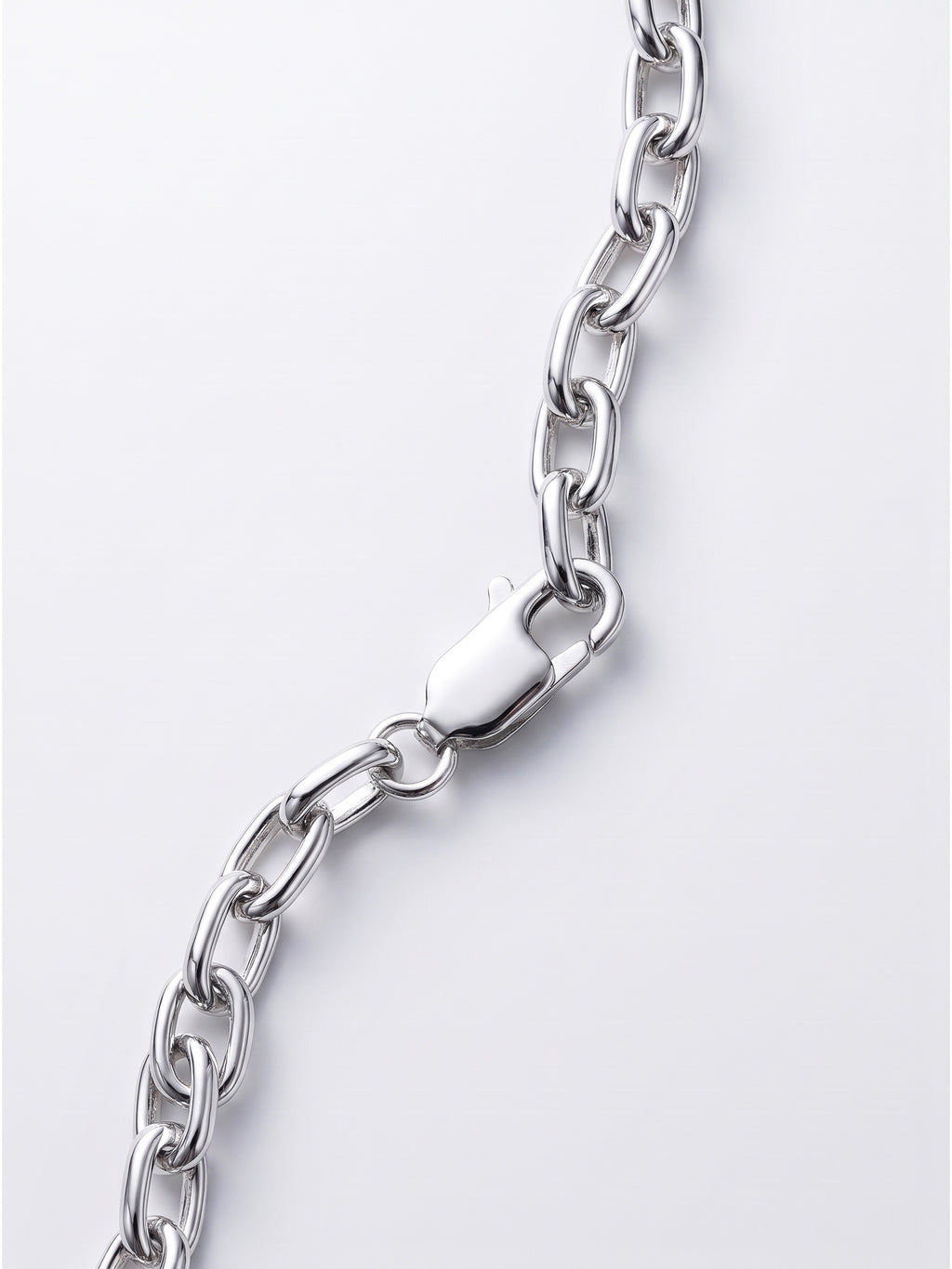 A close-up of a polished silver link chain with a lobster clasp, shown against a clean light gray background.