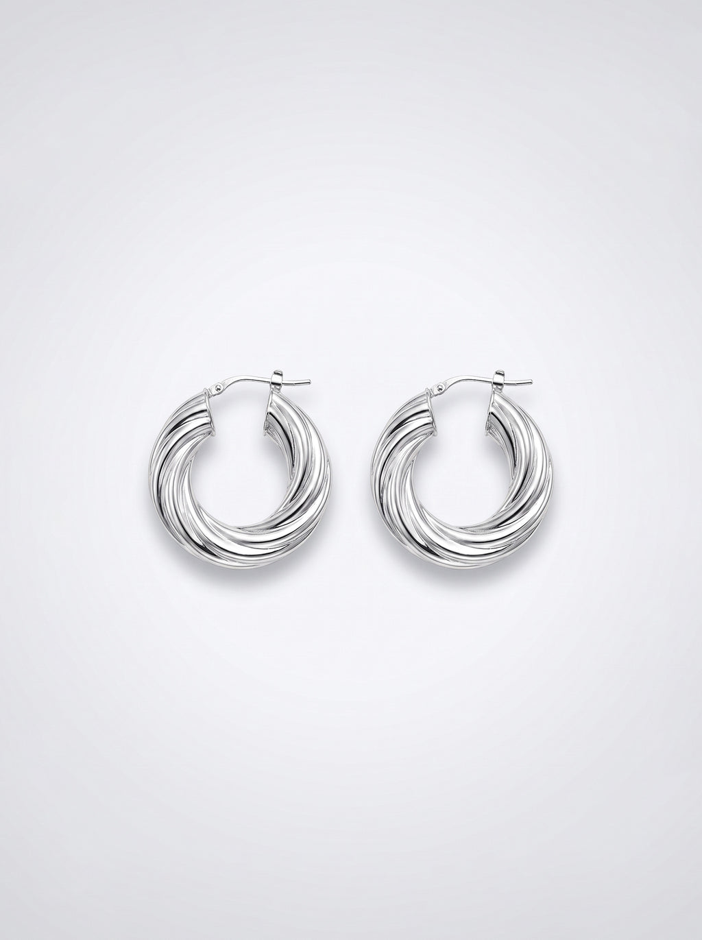 A pair of silver-toned twisted hoop earrings with a polished finish, displayed on a clean light gray background.